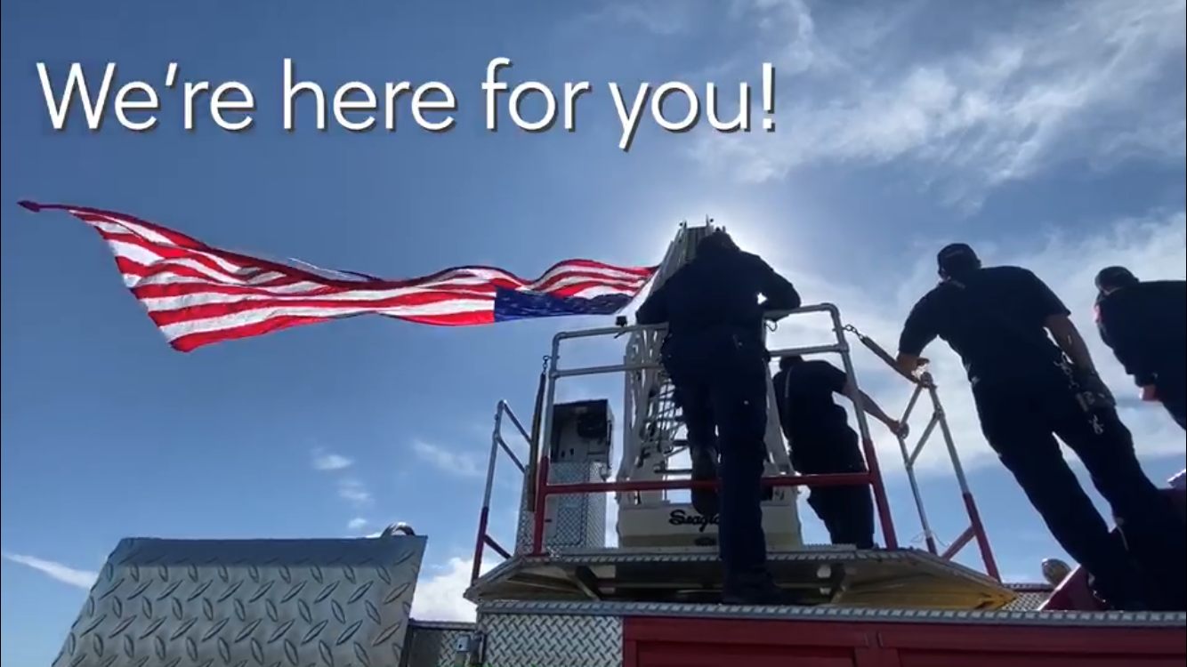 "We're here for you" firefighters standing on fire engine
