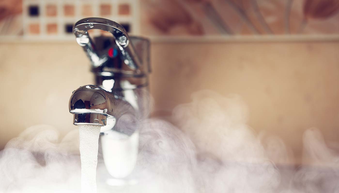 close up of a flowing water faucet, hot water steaming