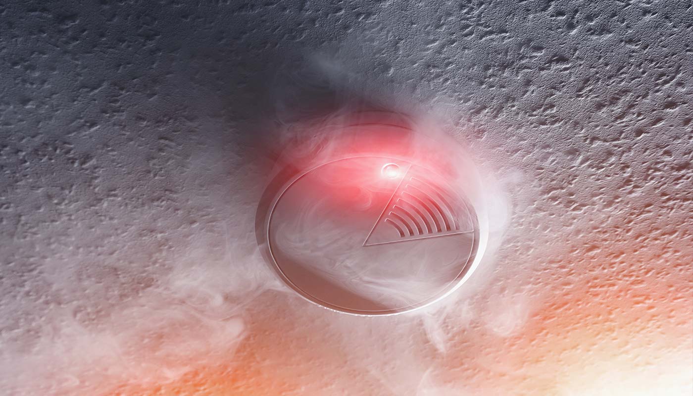 home smoke detector with red alarm glowing
