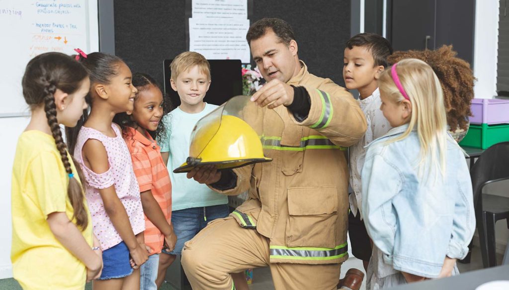 firefighter showing school children his helmet